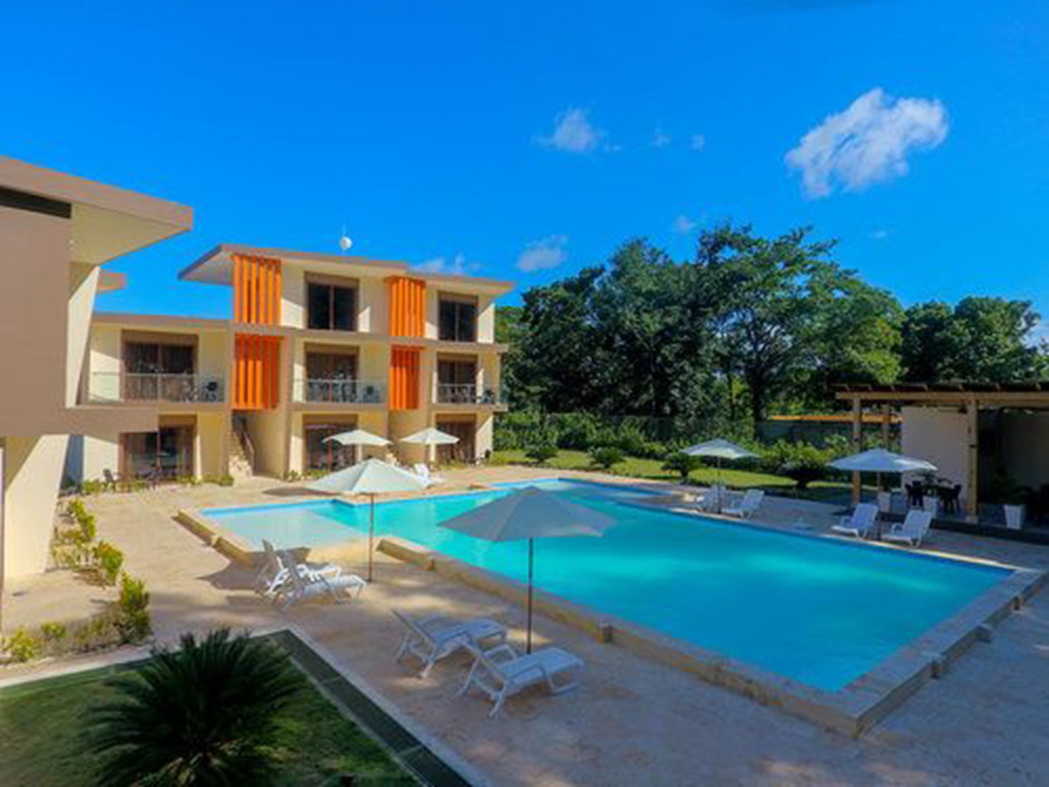 A hotel with a swimming pool, outdoor seating, and a garden area.