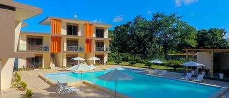 A hotel with a swimming pool, outdoor seating, and a garden area.