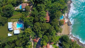 An aerial view of a coastal property with multiple houses, a swimming pool, and a beach area. - Caribbean Diamond Boutique Hotel (Sosúa)
