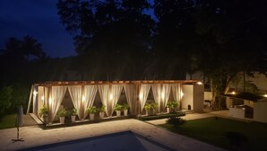 A covered outdoor area with a pool, potted plants, and a pergola with draped fabric. - Caribbean Diamond Boutique Hotel (Sosúa)