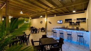An indoor bar area with wooden ceiling beams, a bar counter with stools, and a television mounted on the wall. - Caribbean Diamond Boutique Hotel (Sosúa)