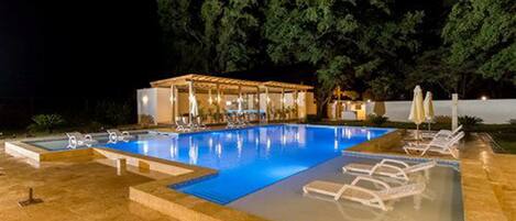 An outdoor swimming pool with lounge chairs and a covered seating area.