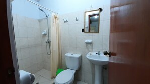 Une petite salle de bain avec douche, toilettes et lavabo.