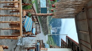 Un espace extérieur aménagé dans un style rustique, avec des meubles en bois et une vue sur un paysage montagneux.