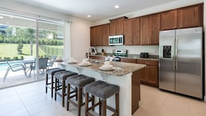 A modern kitchen with a central island, stainless steel appliances, and wooden cabinets. - New House, Near Disney, Private Pool (Kissimmee)
