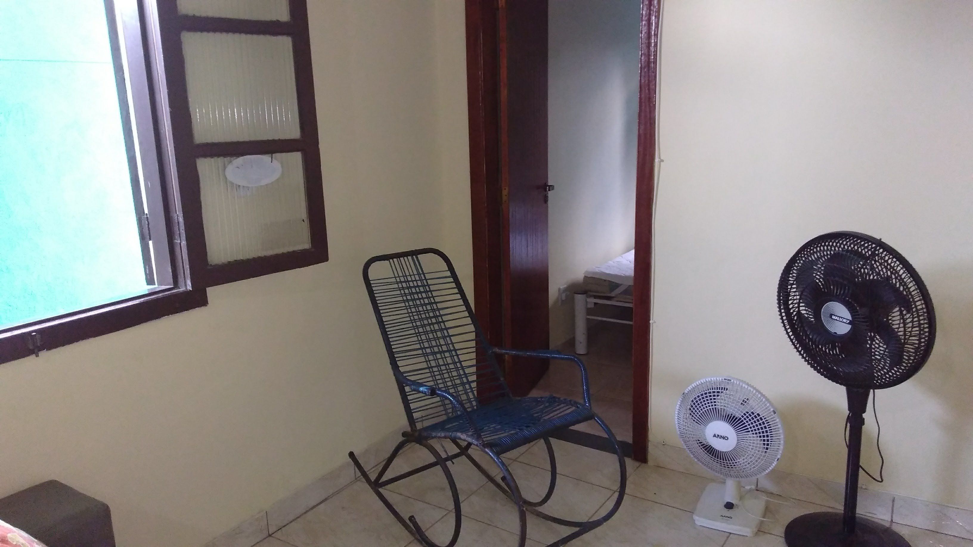 A room with a window, a chair, and two standing fans.
