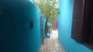 A narrow corridor with blue walls and a stone-tiled floor. - Casa em Cabo Frio (Cabo Frio)