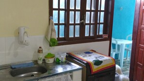 A kitchen with a sink, a window with bars, a white faucet, and a stove. - Casa em Cabo Frio (Cabo Frio)