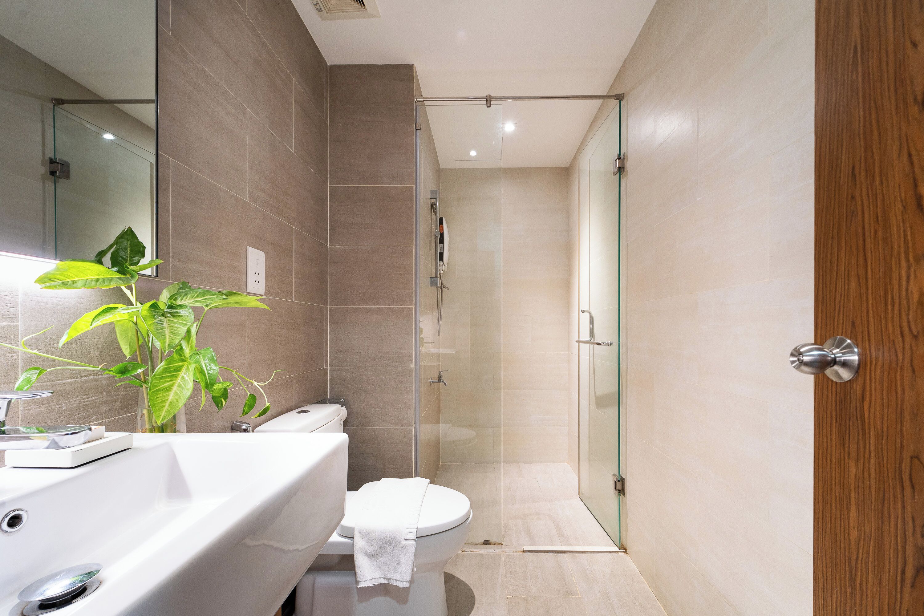 A modern bathroom with a glass shower enclosure, a white sink, and a toilet.