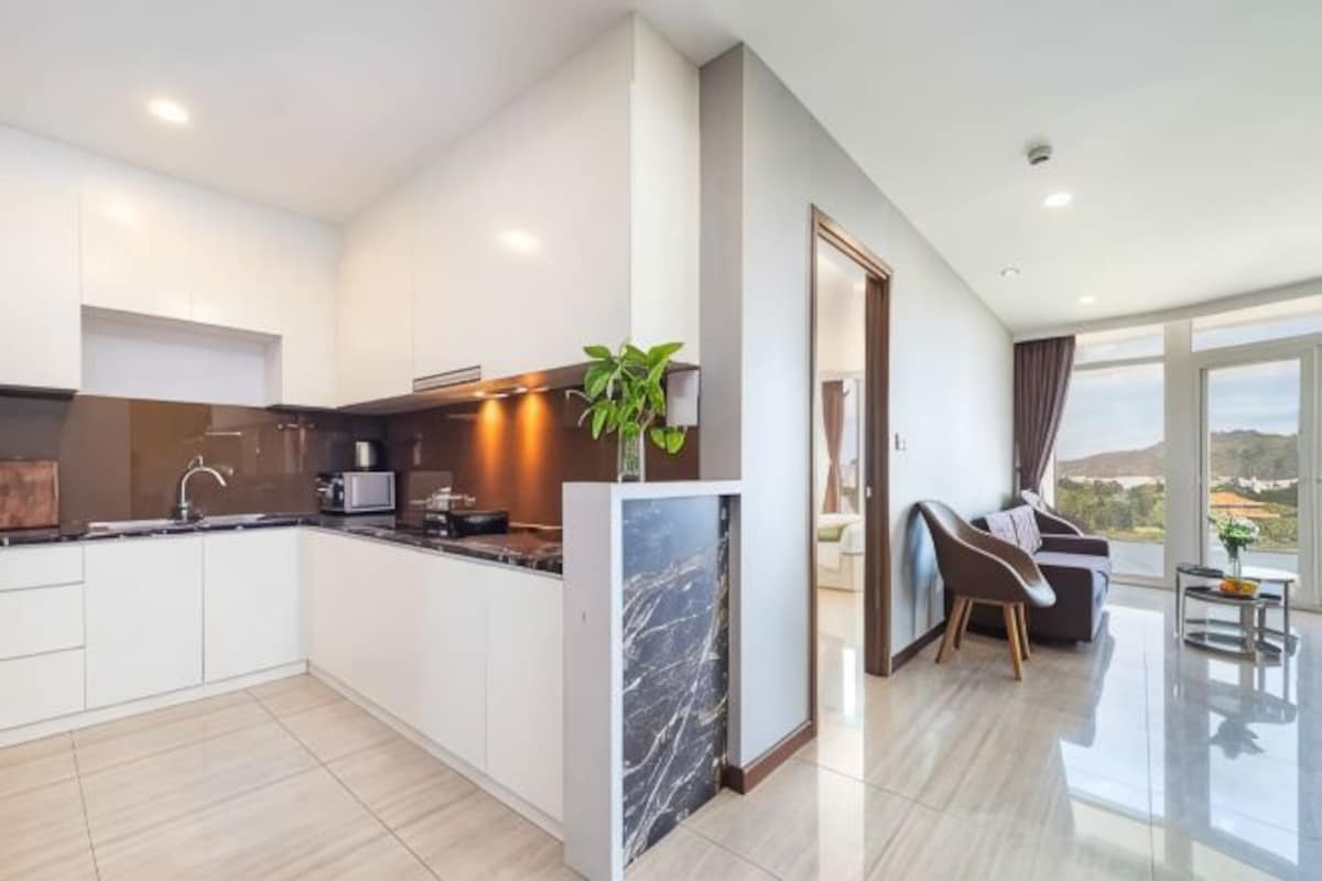 A modern kitchen with a marble island, a dining area with a view, and a living space with a large window.