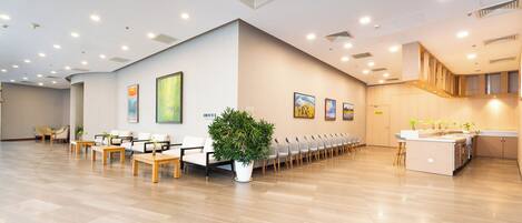 A spacious lobby with a long reception desk, multiple seating areas, and a large potted plant.