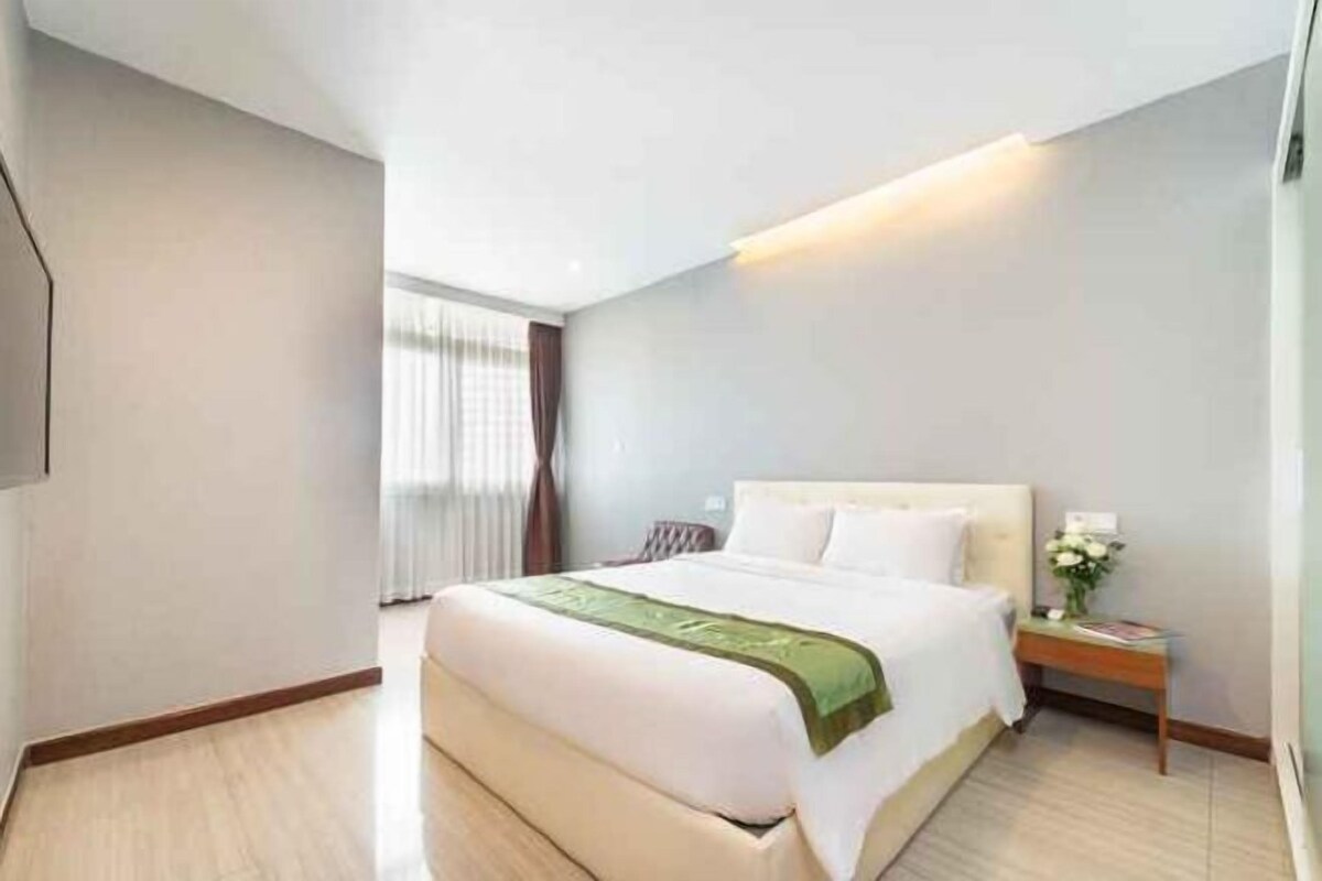 Una habitación de hotel con cama, mesita de noche y una lámpara de pared.