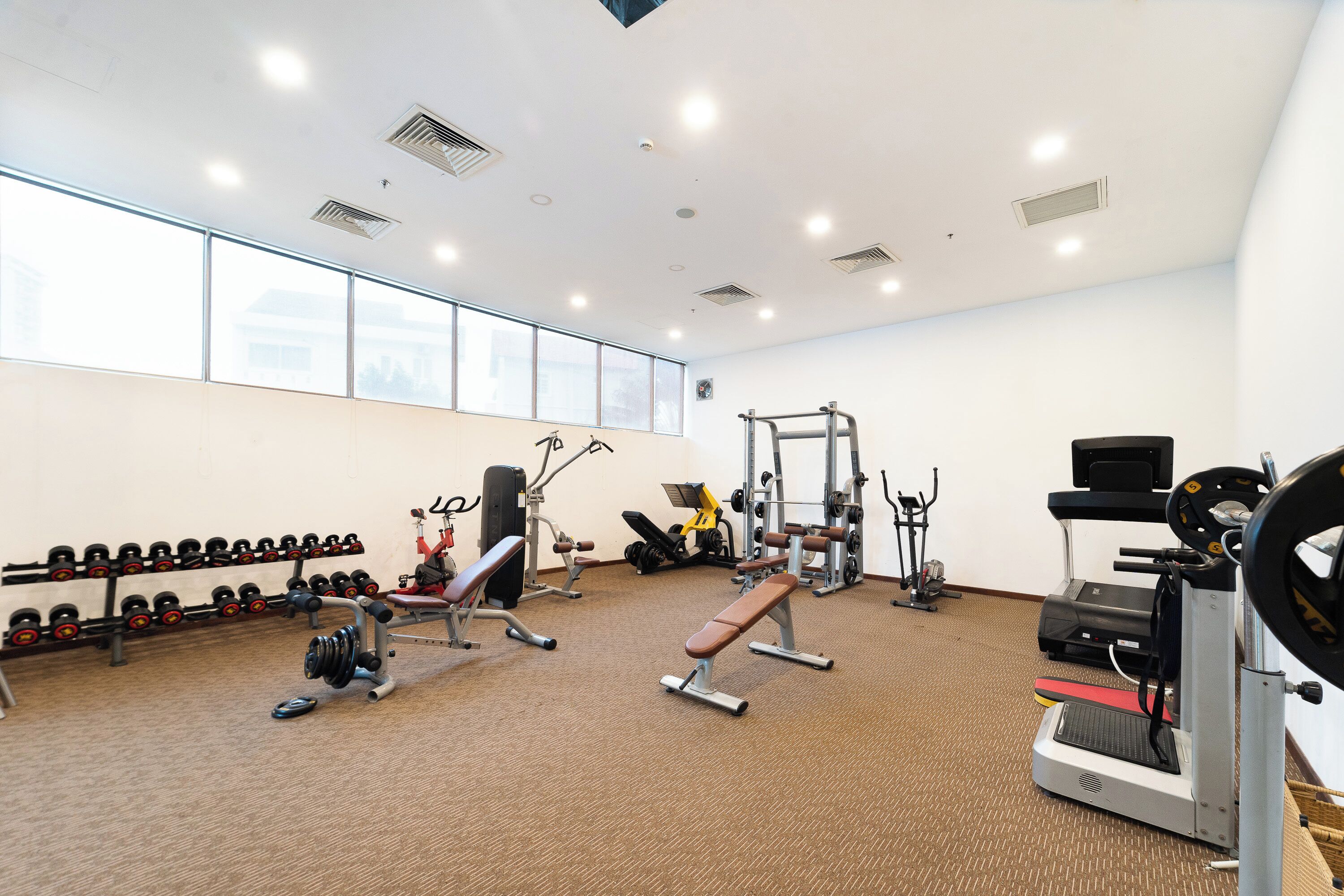 A gym with various exercise equipment, including dumbbells, benches, and cardio machines.
