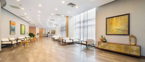 A spacious lobby with a long reception desk, seating area, and large windows.
