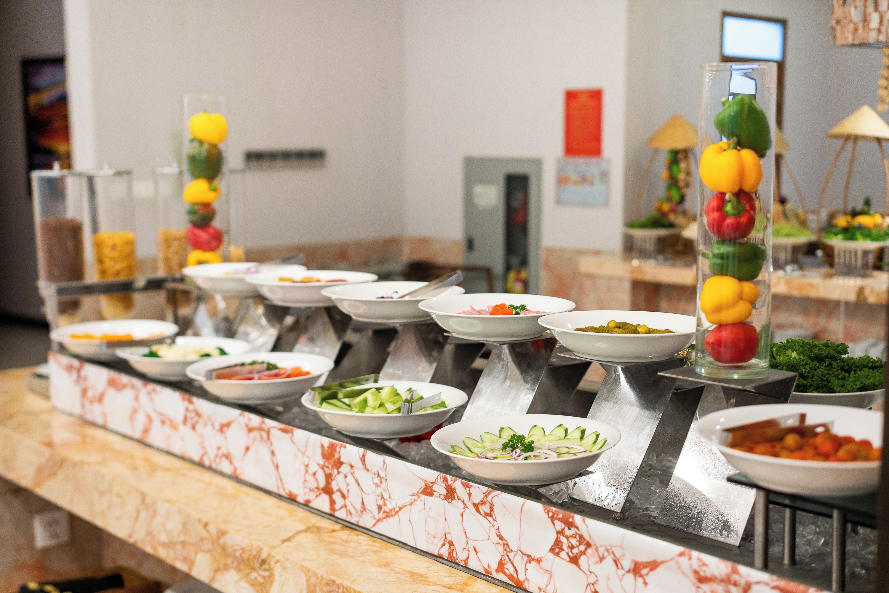 Un bufé con diversas opciones de comida, entre ellas ensaladas y verduras, dispuesto sobre una encimera de mármol.