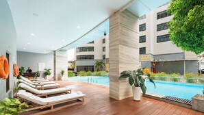 A poolside area with lounge chairs, a pool, and a building in the background. - DIC Star Landmark Vung Tau (Ho Chi Minh City)