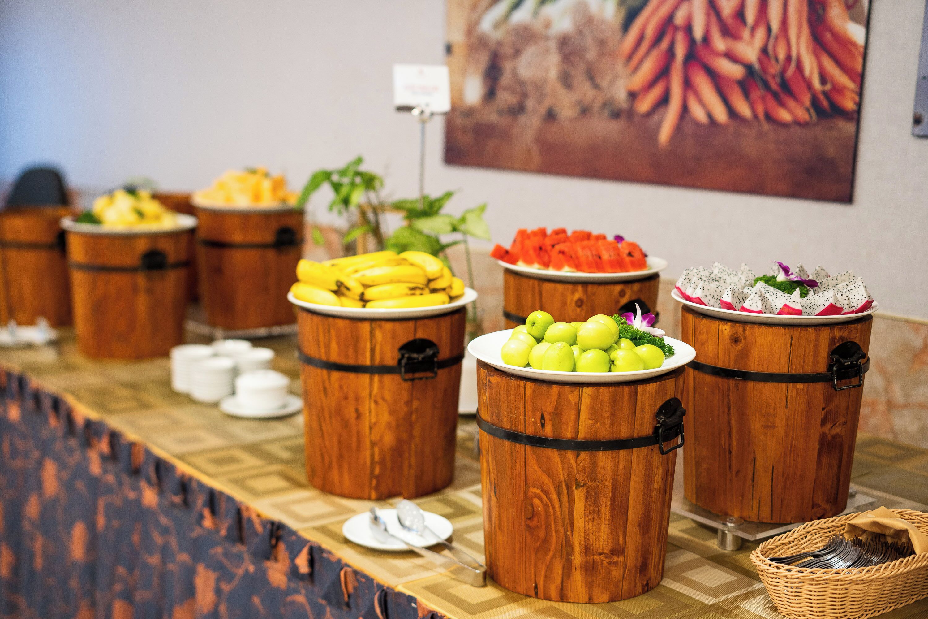 A buffet table with wooden barrels containing fruits and vegetables.