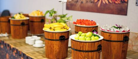 A buffet table with wooden barrels containing fruits and vegetables.