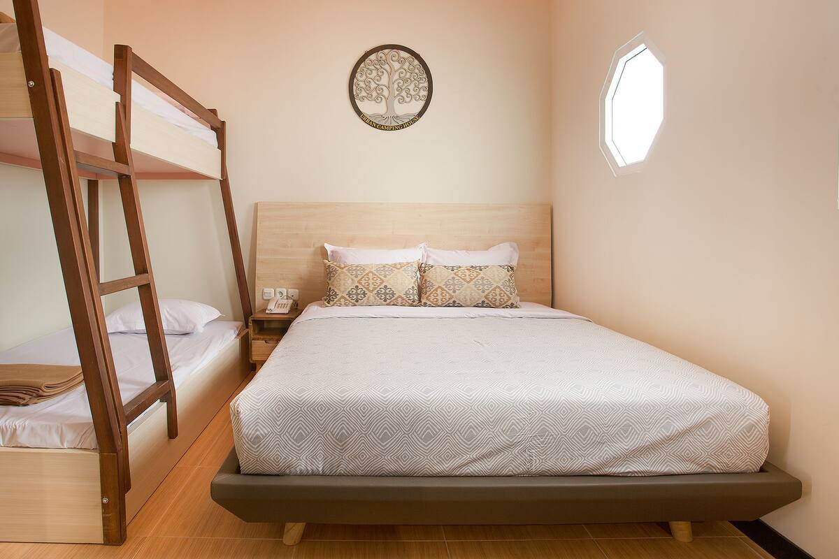 A bunk bed with a wooden ladder, a bedside table with a phone, and a wall-mounted decorative item.