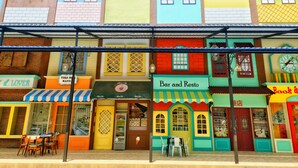 Una hilera de edificios coloridos con diferentes comercios, incluyendo un bar y restaurante, una librería y una cafetería.
