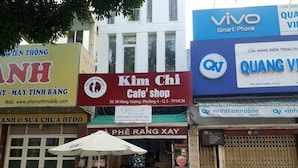 A street view with various shops, including a cafe and a mobile phone store. - Natural House Hostel (Ho Chi Minh City)