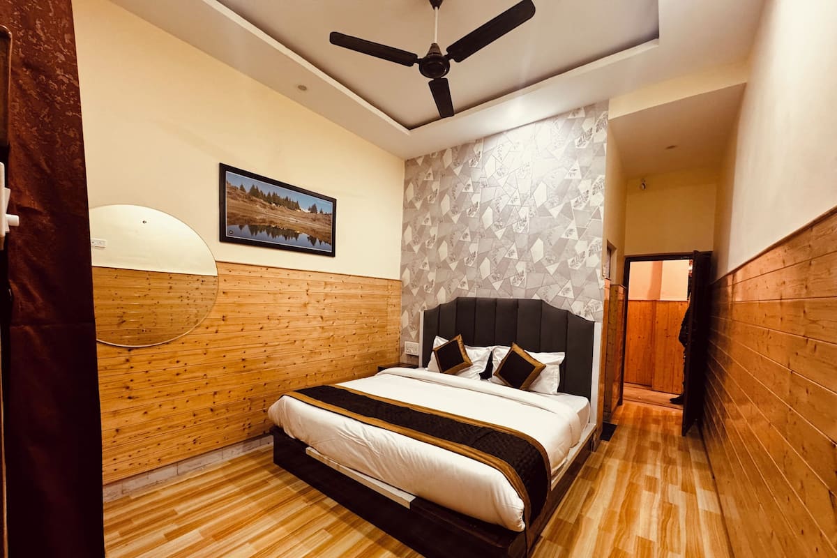 A bedroom with a wooden headboard, a bed with white bedding, a ceiling fan, and a patterned wall.