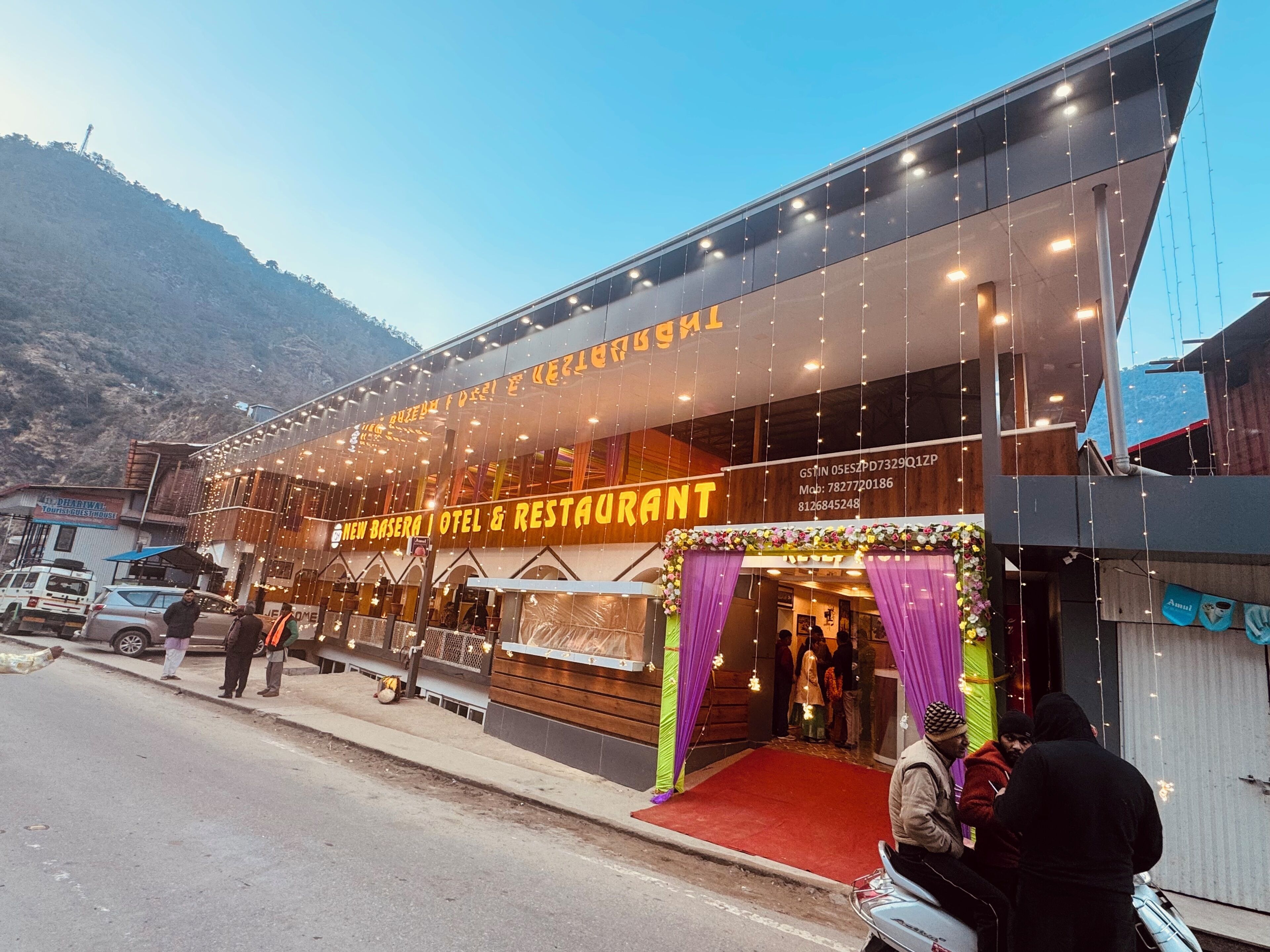 Un edificio con un cartel que dice 'New Basera Hotel & Restaurant' y una entrada con alfombra roja.