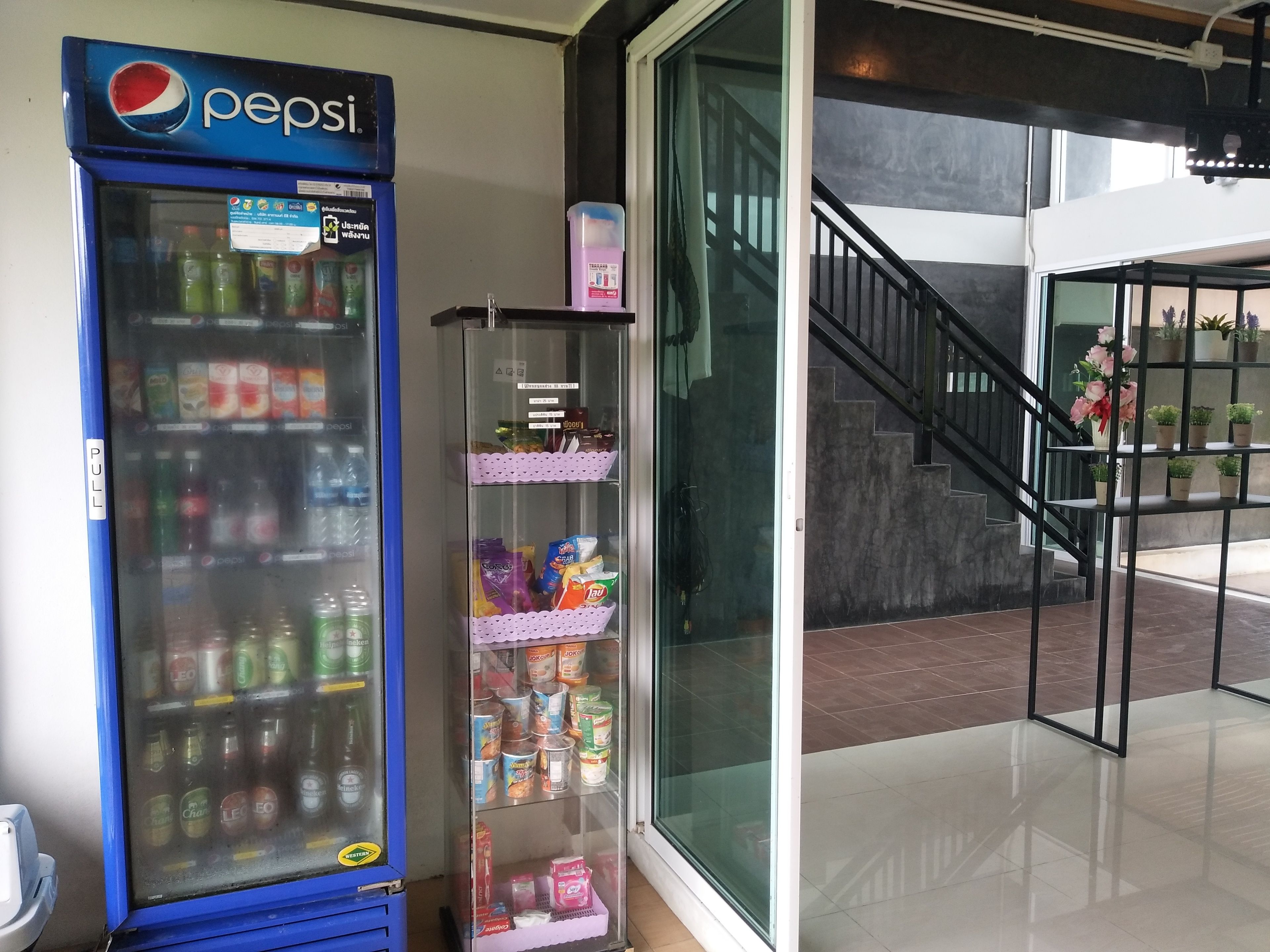 Una máquina expendedora con Pepsi, un expositor de vidrio con aperitivos, y una escalera que lleva a un nivel superior.