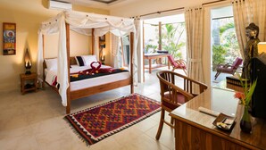 Une chambre à coucher avec un lit à baldaquin, un bureau avec une chaise, une statue de Bouddha et une vue sur l’extérieur.