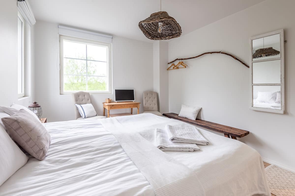 Une chambre avec un grand lit, un bureau, une chaise, une télévision et une fenêtre.