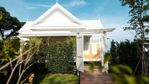 A traditional white house with a tiled roof, surrounded by greenery and a wooden pathway leading to the entrance. - De Chaochom Hua Hin (Hua Hin)