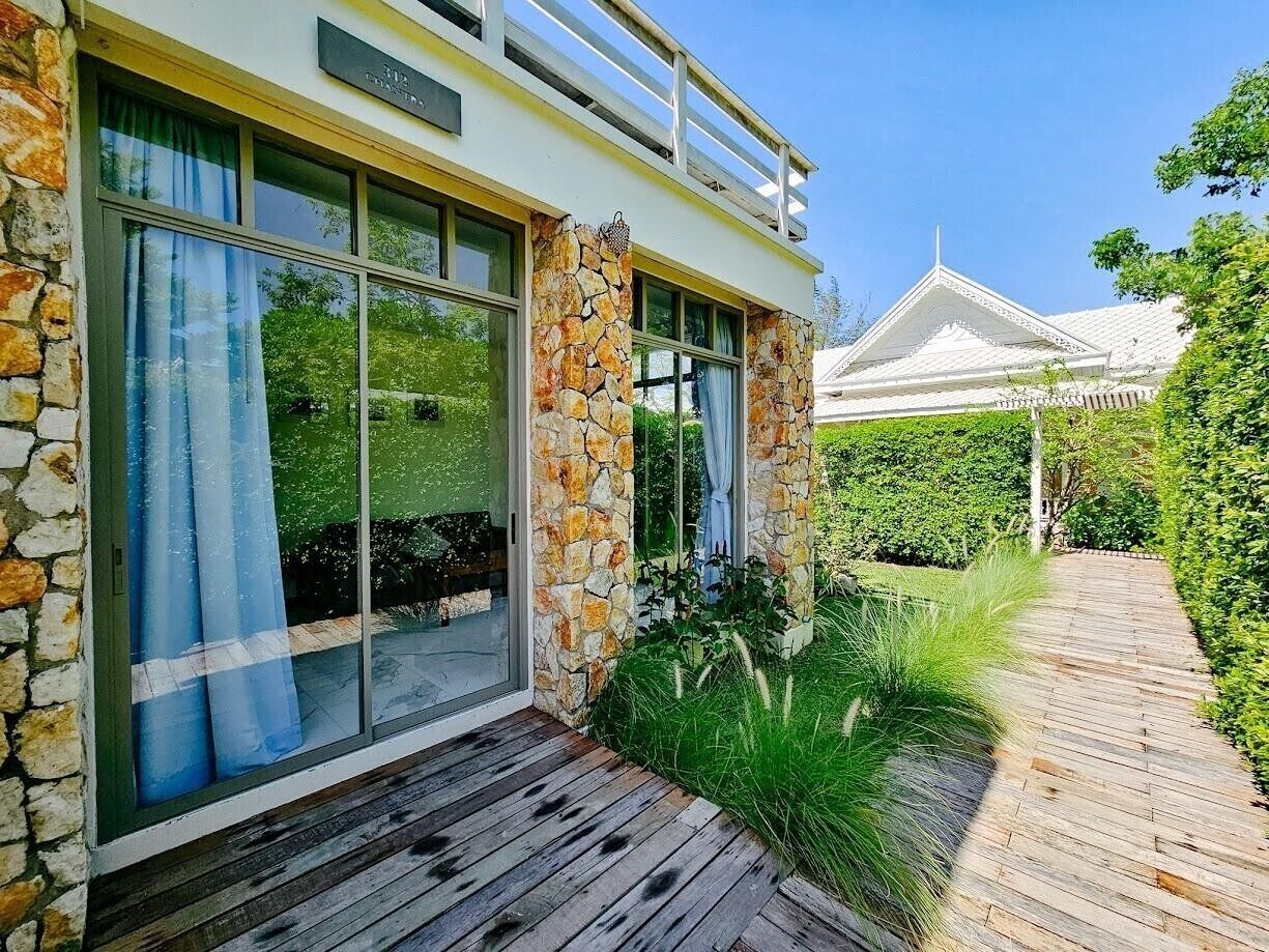 A modern house with a stone facade, large glass windows, and a wooden deck.