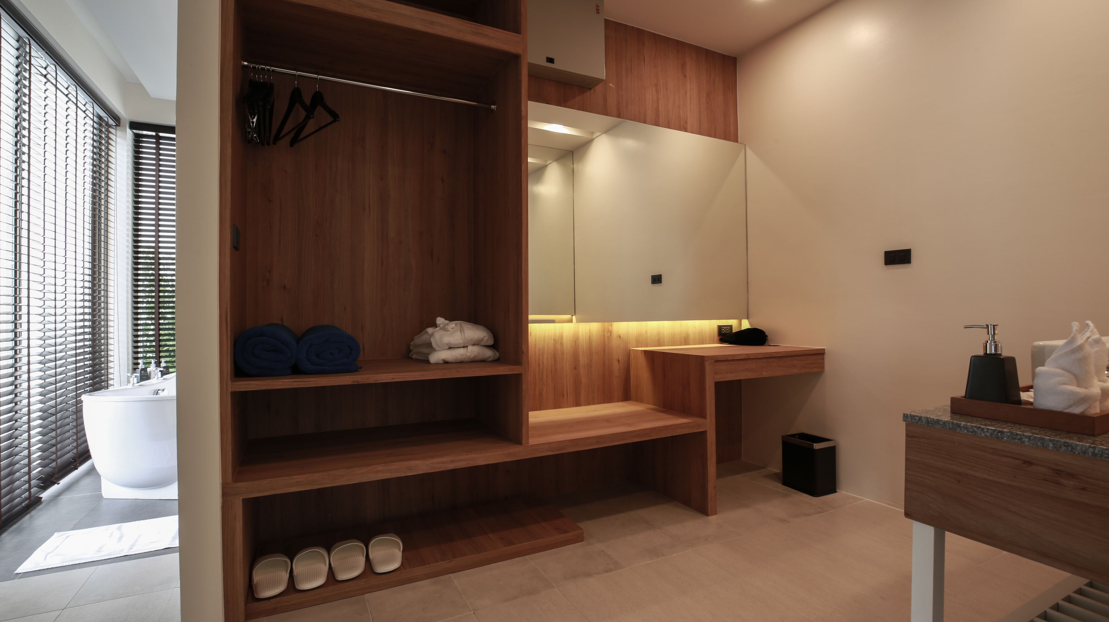 A modern bathroom with wooden shelving, a large mirror, and a sink.