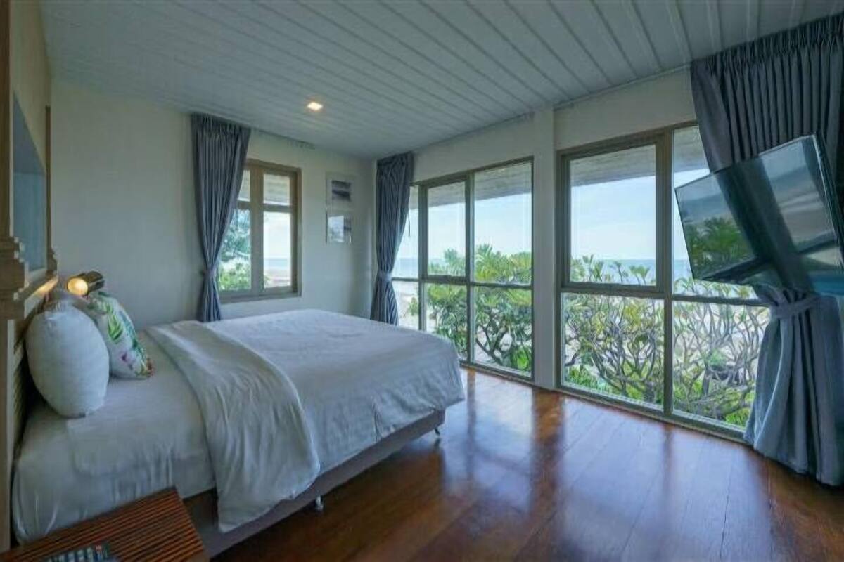 A bedroom with a large bed, a TV, and a view of the outdoors.