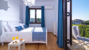 Quarto com cama, mesa de café da manhã, janela com cortinas e vista para o verde lá fora.