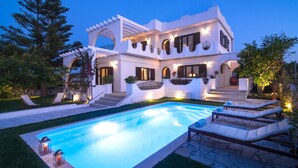 Uma villa moderna com piscina, área de estar externa e entrada bem iluminada.