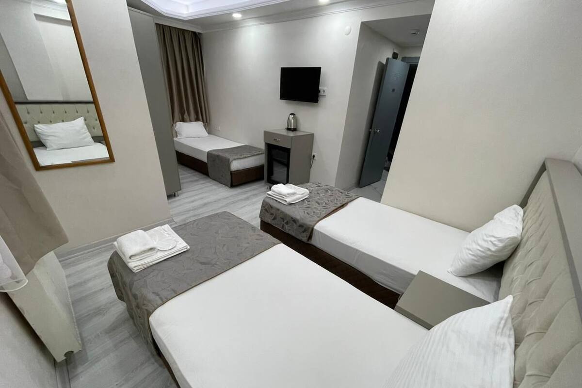 Habitación de hotel con dos camas, televisión, escritorio pequeño y espejo.