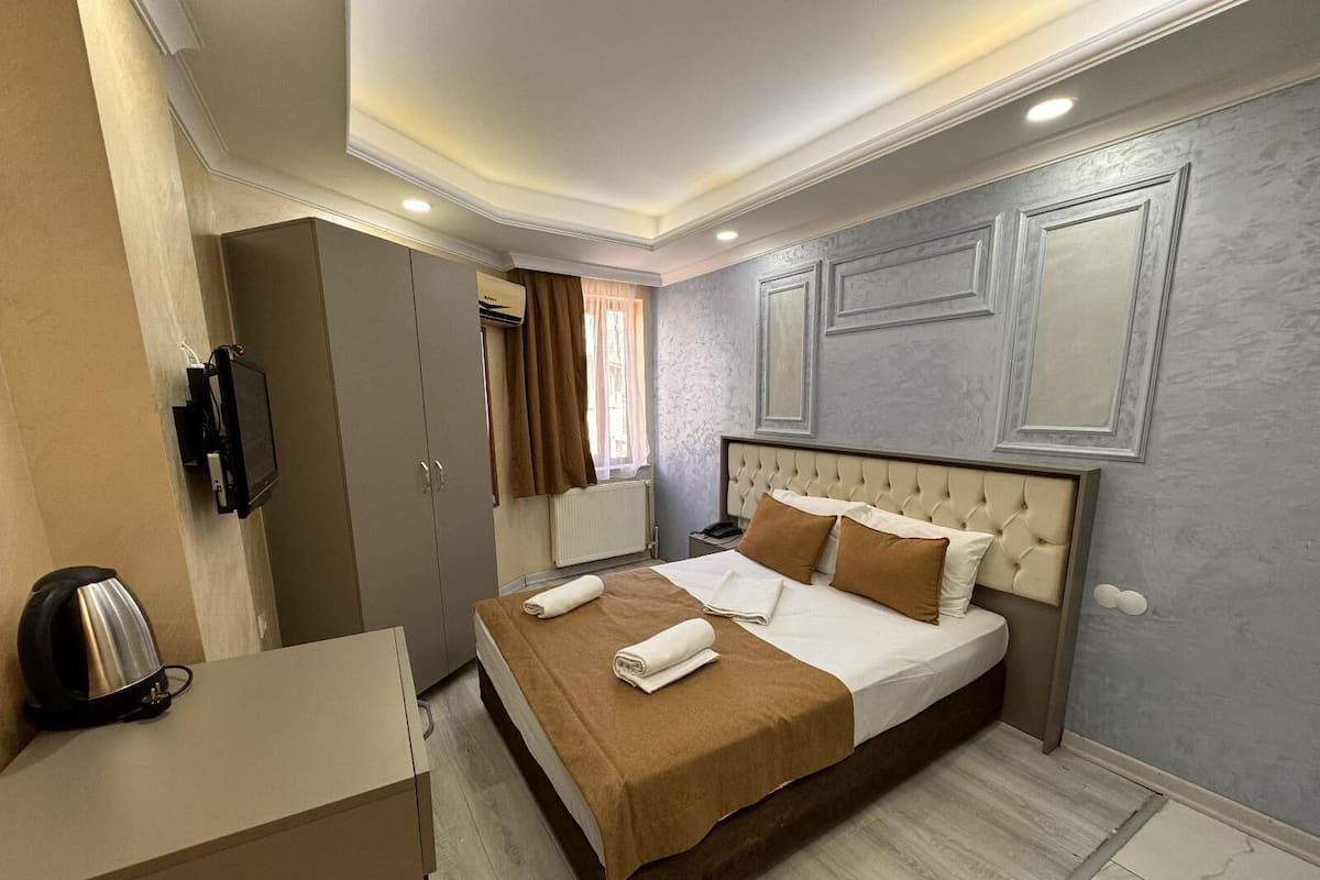 Una habitación de hotel con cama, escritorio, televisión y armario.