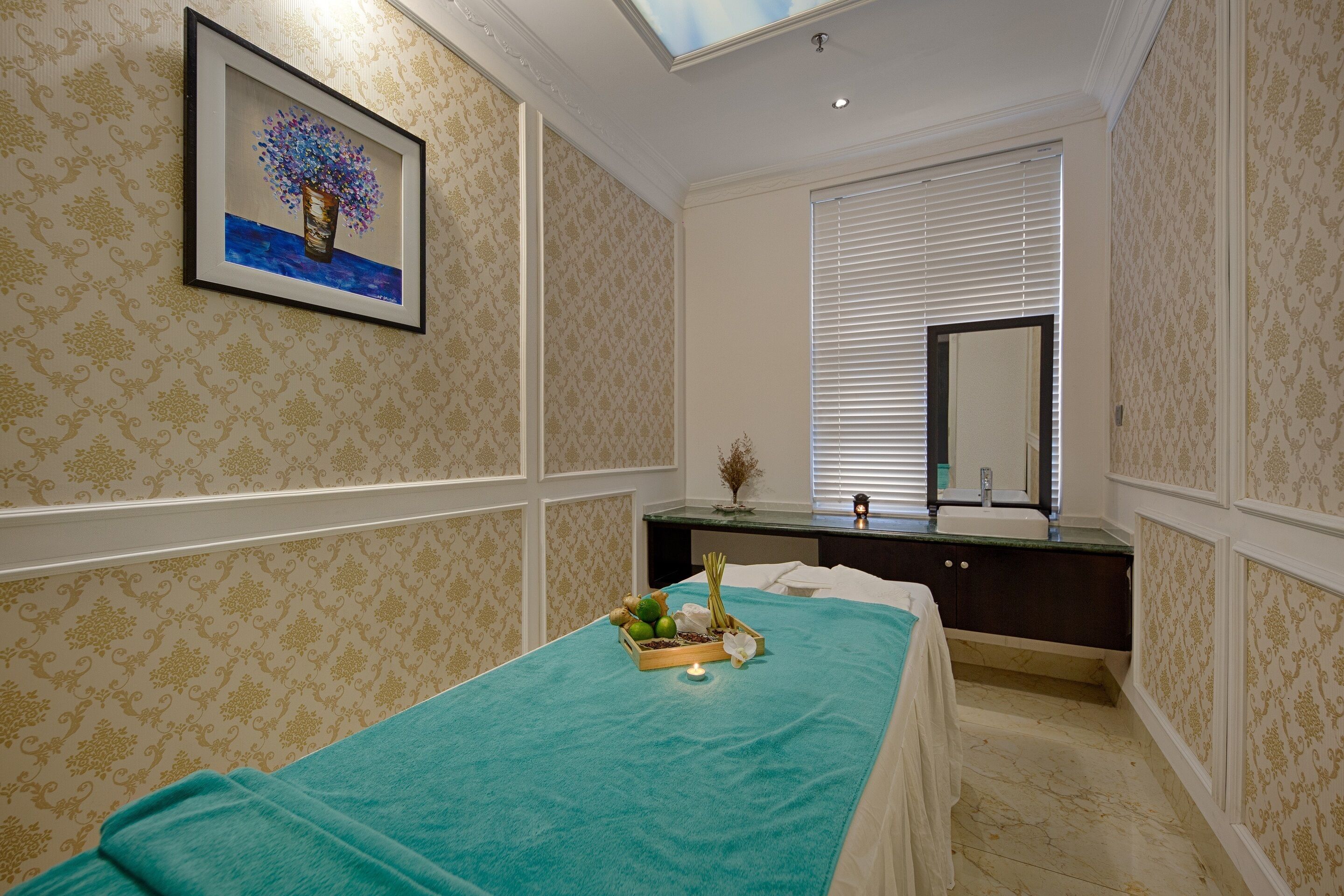 A spa room with a bed, a vanity, a mirror, and a framed artwork on the wall.