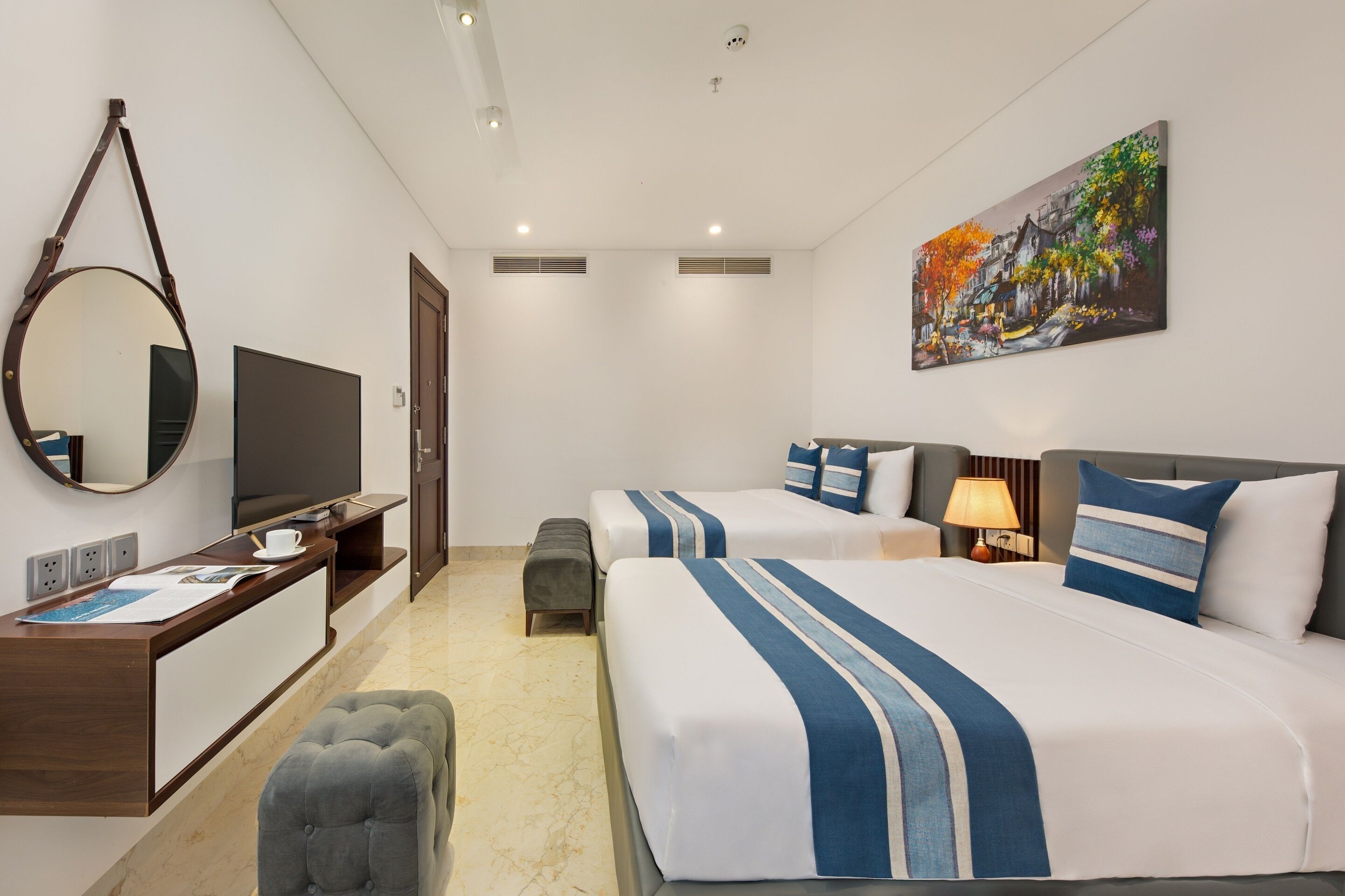 A hotel room with a bed, two bedside tables, a desk with a TV, a mirror, and a painting on the wall.