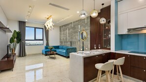 A modern kitchen with a marble countertop, bar stools, and a city view. - Eden Hotel (Da Nang)
