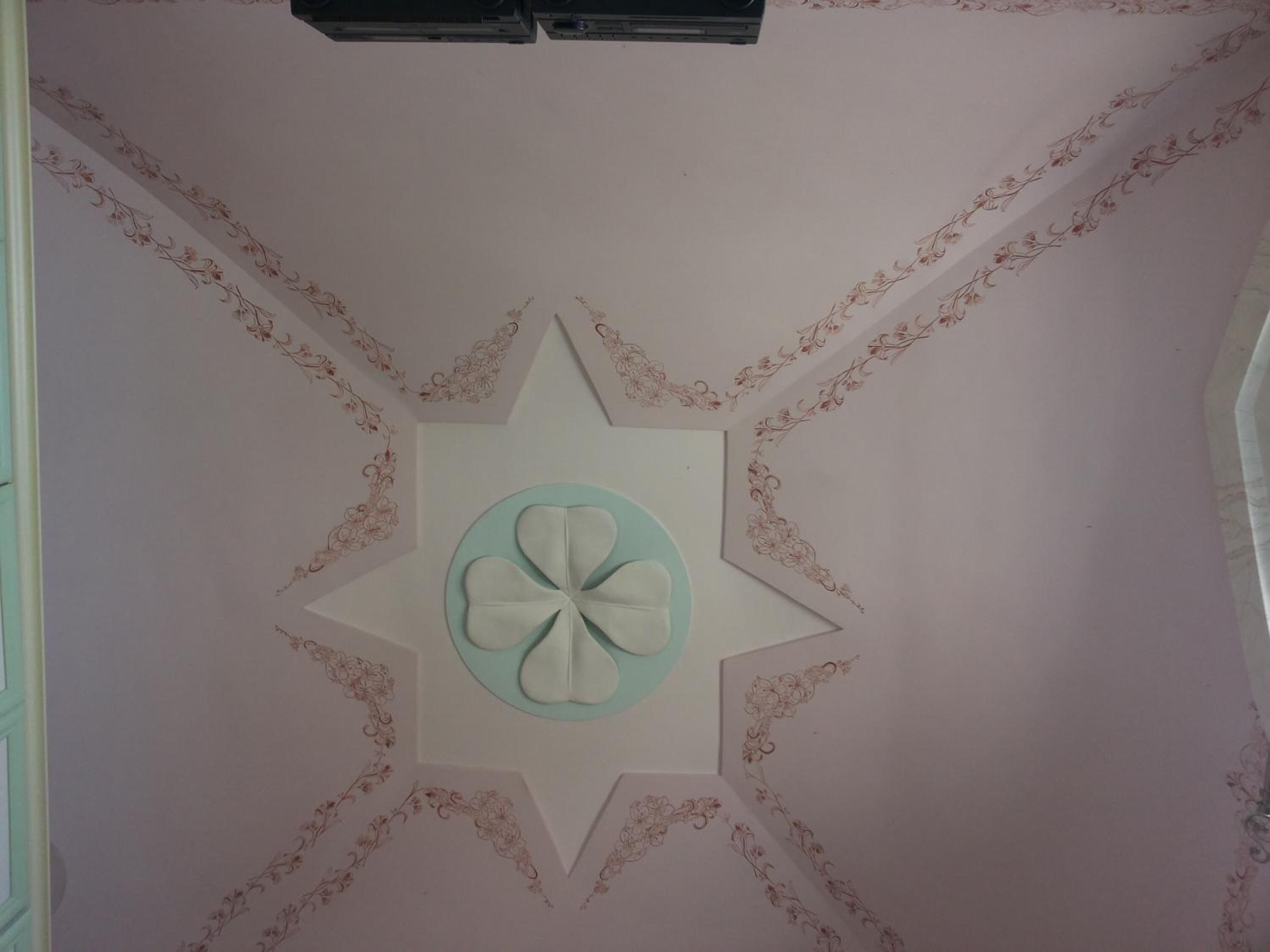 A ceiling with a central floral design surrounded by a star pattern.