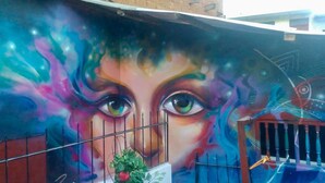 A colorful mural with abstract patterns and a fence in the foreground. - Déjà Vu Backpackers (Chachapoyas)