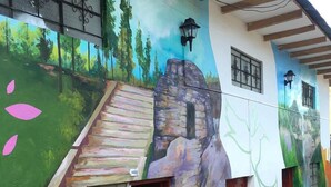 A building with a mural of a staircase leading to a door, a window, and a lamp post. - Déjà Vu Backpackers (Chachapoyas)