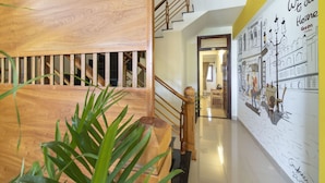 A modern interior with a wooden staircase, a polished floor, and a mural depicting a cityscape. - Green Garden Hoi An Villa (Da Nang)