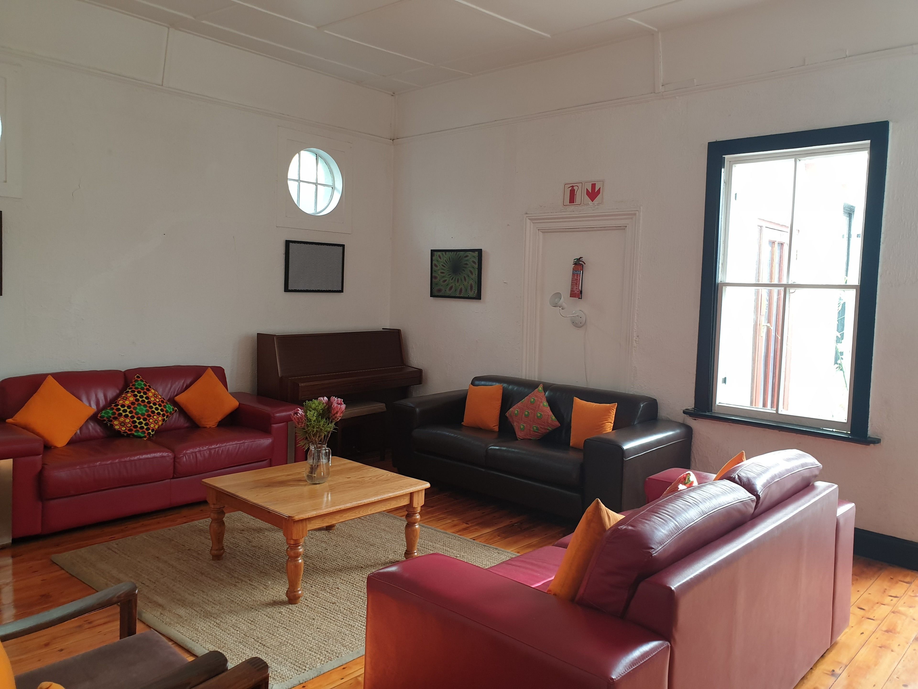 A living room with a red sofa, a black sofa, a wooden coffee table, and a piano.