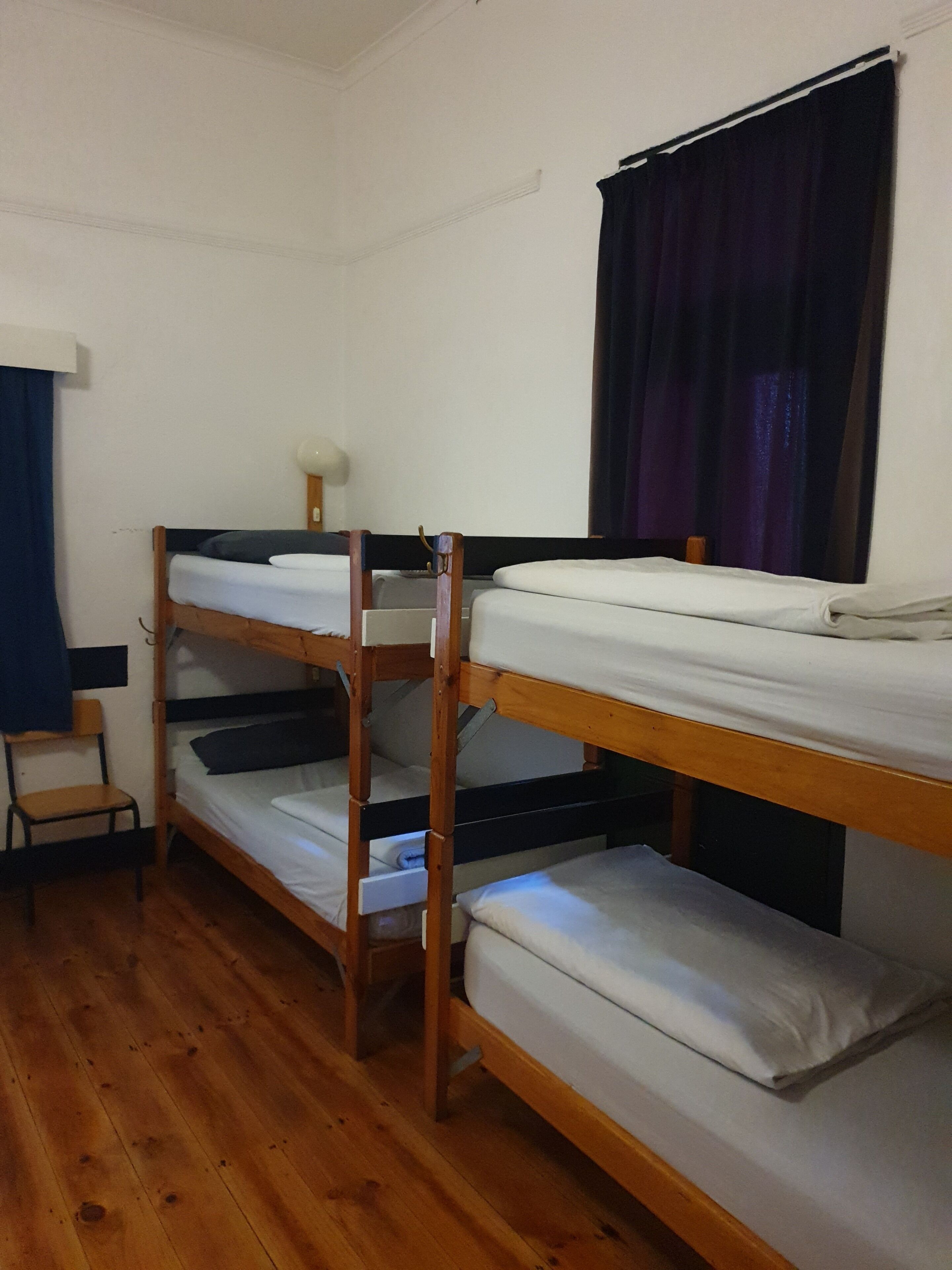Une chambre avec des lits superposés, une chaise et une fenêtre avec des rideaux.