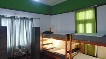 A bunk bed room with a fan, curtains, and a window with green curtains.