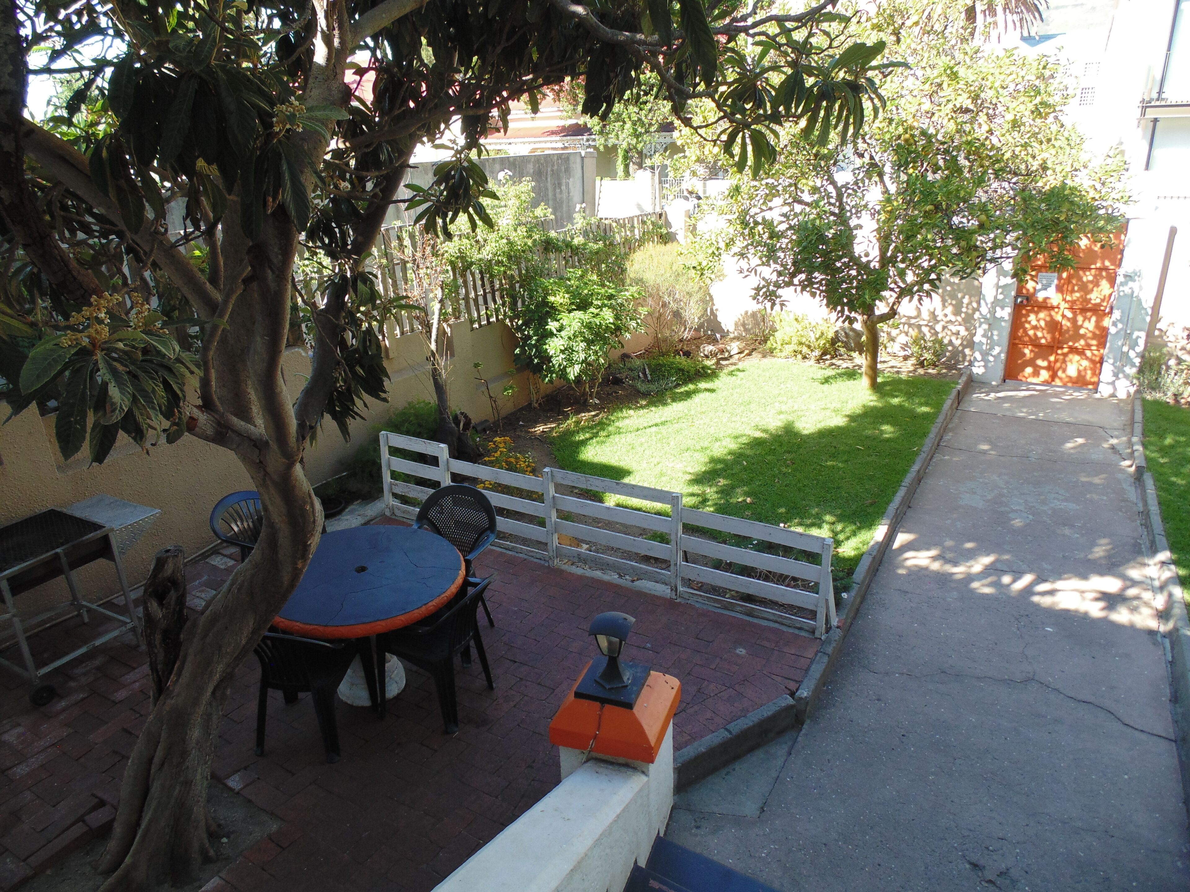 An outdoor patio with a round table, chairs, and a bench.