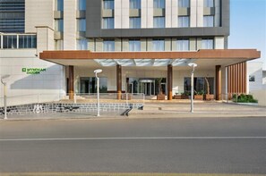 A modern hotel entrance with a covered walkway, a glass entrance, and a sign for Wyndham Garden.